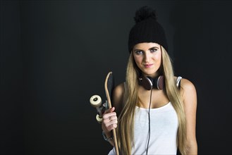 Cool young woman with a skateboard and headphones