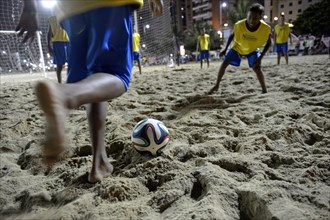 Young people playing football in the evening at the beach