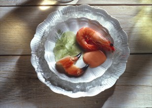 Prawns in their shell with crab claws and cucumber on white plate