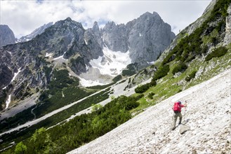 Female hiker crossing a snowfield on the Wilder-Kaiser-Steig hiking trail