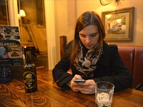 Woman looking at her smartphone in a pub