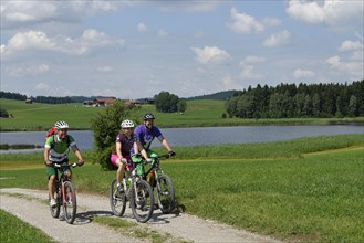Cyclists on bike tour on Trollweiher pond in Seeg