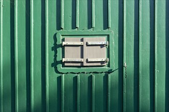 Closed shutters of a green wooden hut