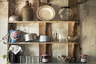 Old pots and dishes on wooden shelves in the kitchen of an old French farmhouse