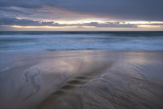 Water flows into the sea at the sandy beach