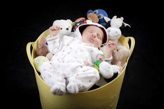 Baby sleeping in a bucket full of stuffed animals
