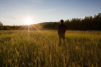 Man standing in a field at sunset