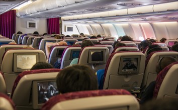 Cabin of a passenger aircraft with entertainment screens and passengers