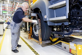 Employee mounting a tyre on a chassis at MAN Truck and Bus AG