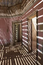 Light passing through the laths of a decaying house in the former diamond miners settlement that is slowly covered by the sand of the Namib Desert