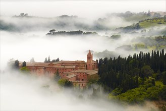 Monte Oliveto Maggiore abbey with mist-shrouded valleys