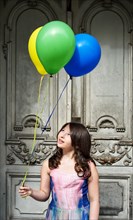 Girl holding balloons in front of an old door