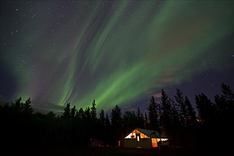 Curtains of northern polar lights and iluminated cabin