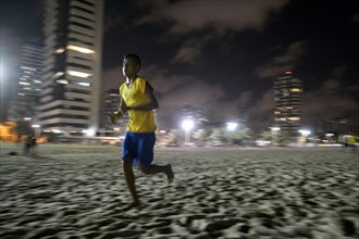 Brazilian teenager training at night on the beach for the Street Children World Cup 2014