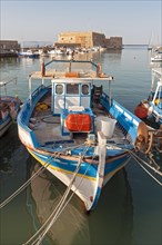 Fishing boat in front of Koules Fortress or Rocca al Mare