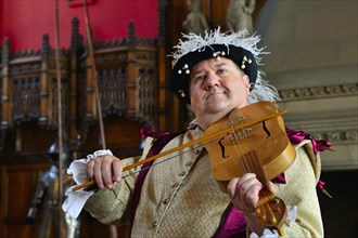 Musician in period costume performing on a medieval fiddle