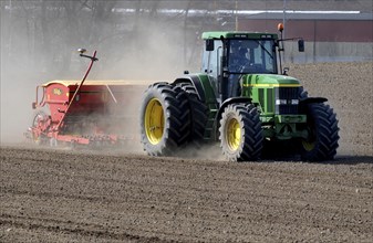 Tractor with sowing machine works on dusty fields at spring farming. Kopingebro