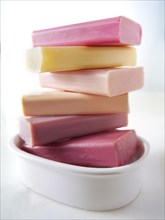 Bars of coloured hand made soap piled in a soap dish
