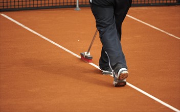 Groundsman cleans the lines on a tennis court