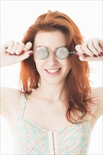 Young red-haired woman holding tea infusers in front of her eyes