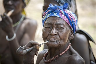 An elderly woman from the Koma people smoking a pipe