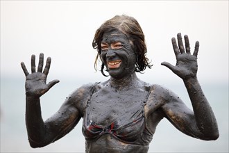 Female tourist covered in salty mud from the Dead Sea