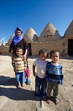 Mother and children in front of their beehive adobe buildings