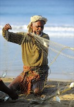 Fisherman taking small fish out of the net