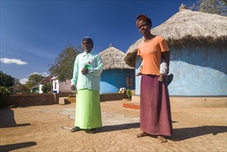 Man and woman with child standing in front of adobe houses