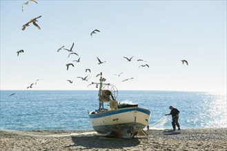 Fisherman with a fishing boat on the beach of Noli