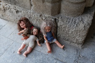 Three forgotten children's dolls beside a medieval column