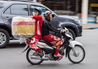Boy and man transporting a large object on a motorcycle