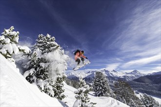 Snowboarder jumping over trees