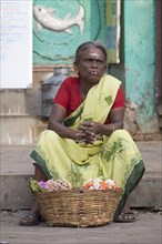 Local woman sitting in front of a temple selling floral decorations