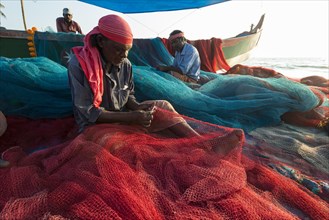 Fishermen repairing fishing nets on the beach