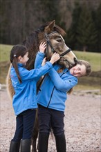 Two girls standing beside a pony