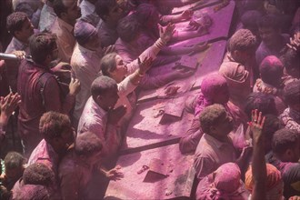 Devotees covered in coloured powder praying