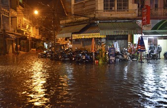 Street scene with a flooded road during heavy monsoon rain at night