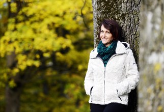Smiling woman standing at a tree in autumn