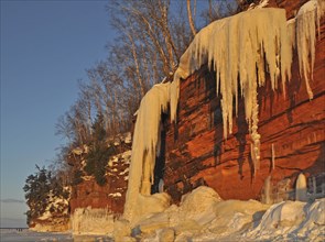 Frozen waterfall and icicles hanging from red sandstone cliff