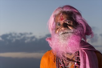 Portrait of an old man with a pink beard at the Holi festival