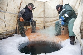 Two elderly fishermenfishing on the frozen Lake Baikal