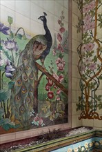 Art Deco tile mural with a peacock and floral scrolls