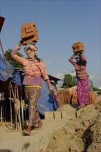 Female construction workers carry bricks on their heads