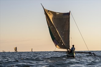 Native fisherman in traditional Pirogue outrigger boat on open sea