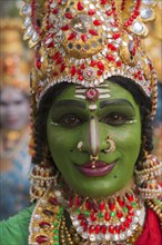 Hindu temple dancer wearing gold jewelry with his face painted green