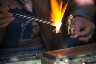 Glassblower working on a glass figure with a flame