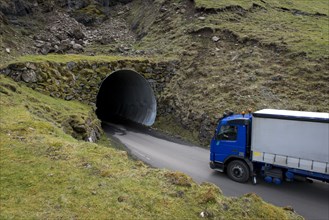 Truck driving into a single-track tunnel between Husar and Mikladalur