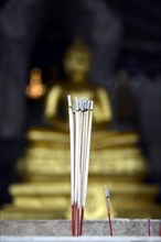 Burning incense sticks in front of a Buddha statue