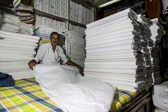 A salesman is displaying white material at Mangaldas Market